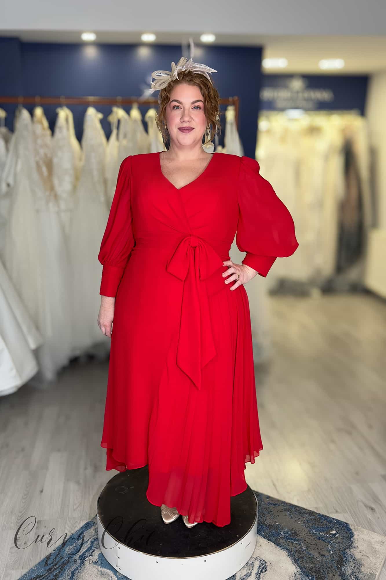 Plus size woman wearing red Veni Infantino chiffon high-low dress with bishop sleeves and waist bow, mother of the bride occasion wear, Curvy Chic Boutique Belfast
