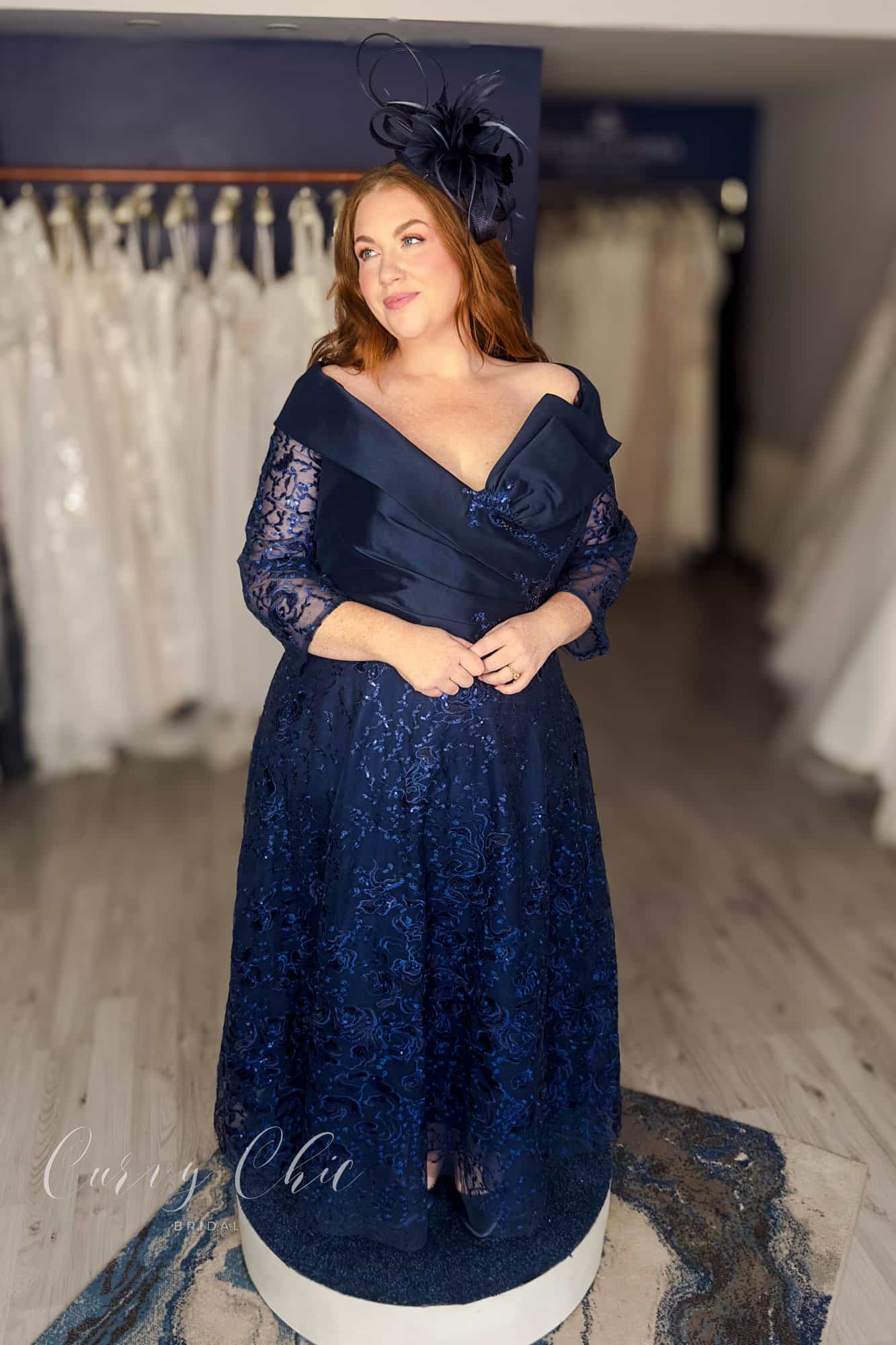 Plus size model wearing navy Bardot lace midi dress by Veni Infantino at Curvy Chic Bridal 992532