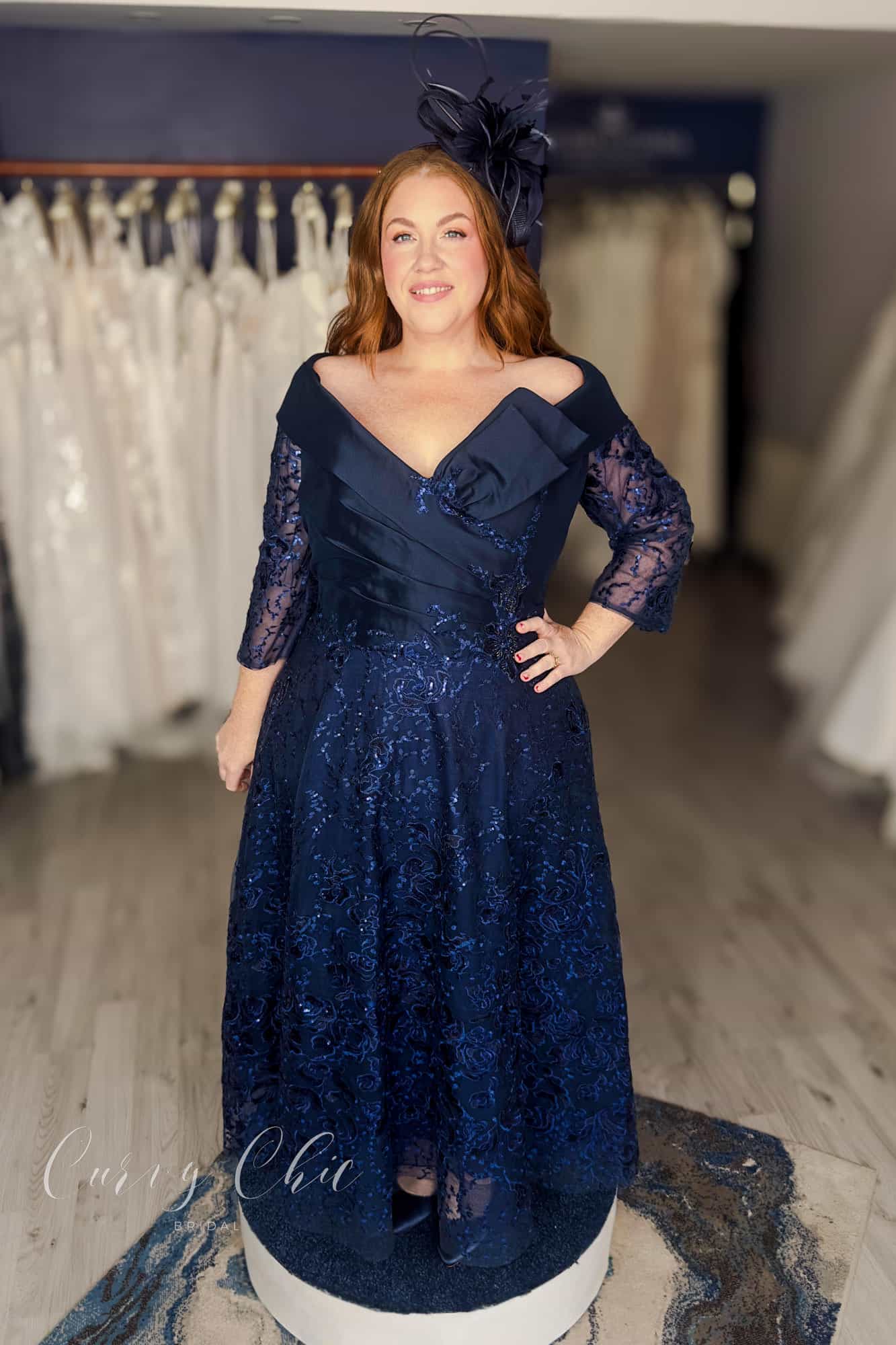 Plus size model wearing navy Bardot lace midi dress by Veni Infantino at Curvy Chic Bridal 992532 front view