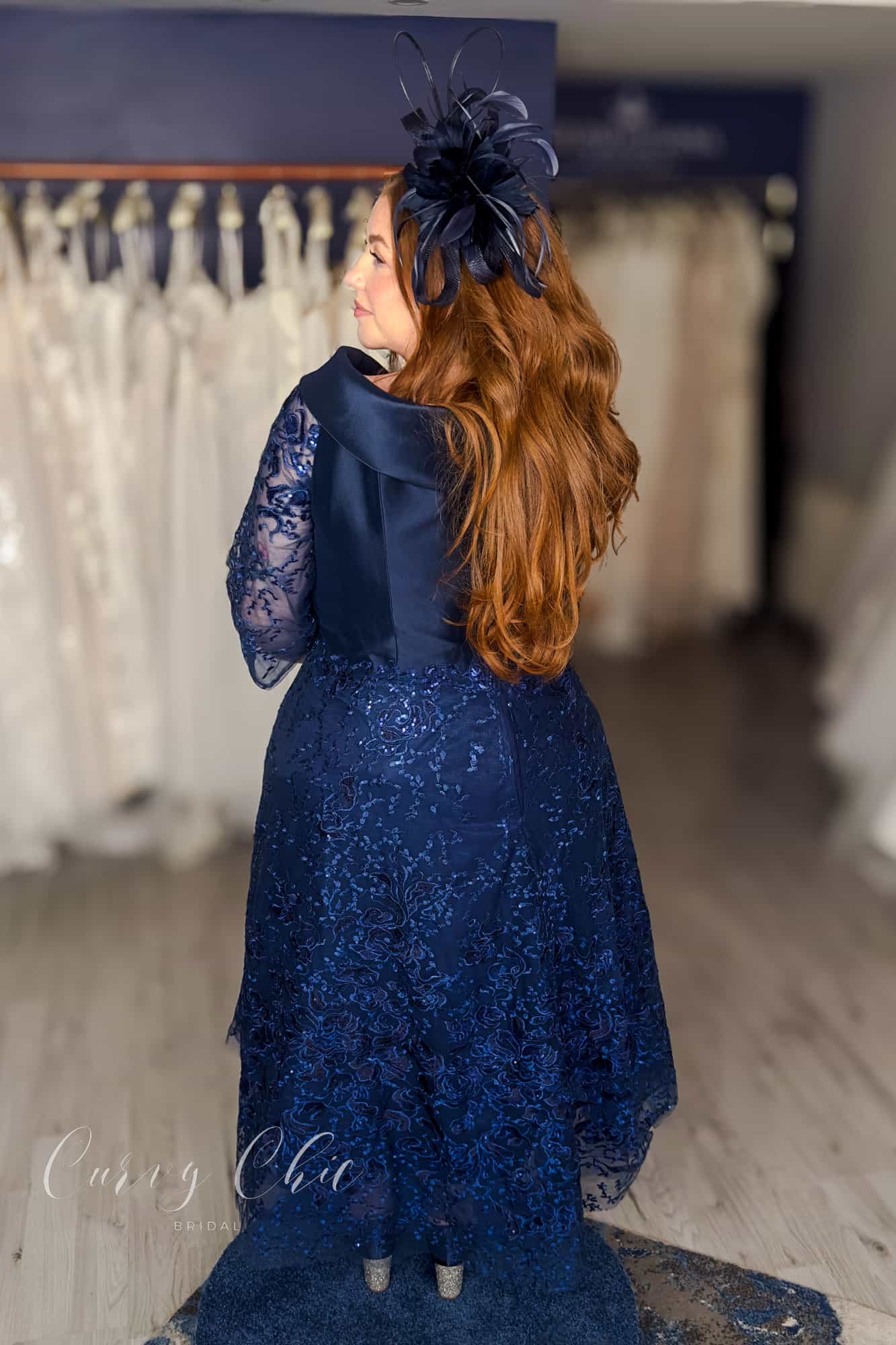 Plus size model wearing navy Bardot lace midi dress by Veni Infantino at Curvy Chic Bridal 992532 back view
